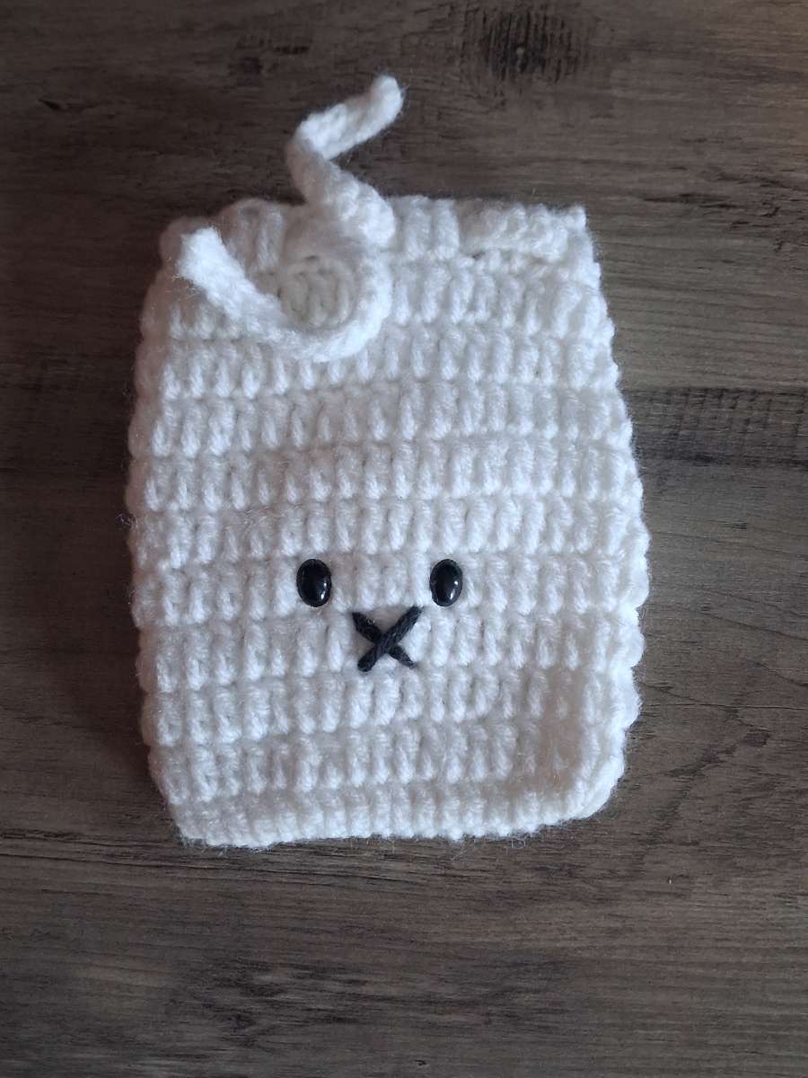 Cream crocheted drawstring pouch with a stitched face and bead eyes
