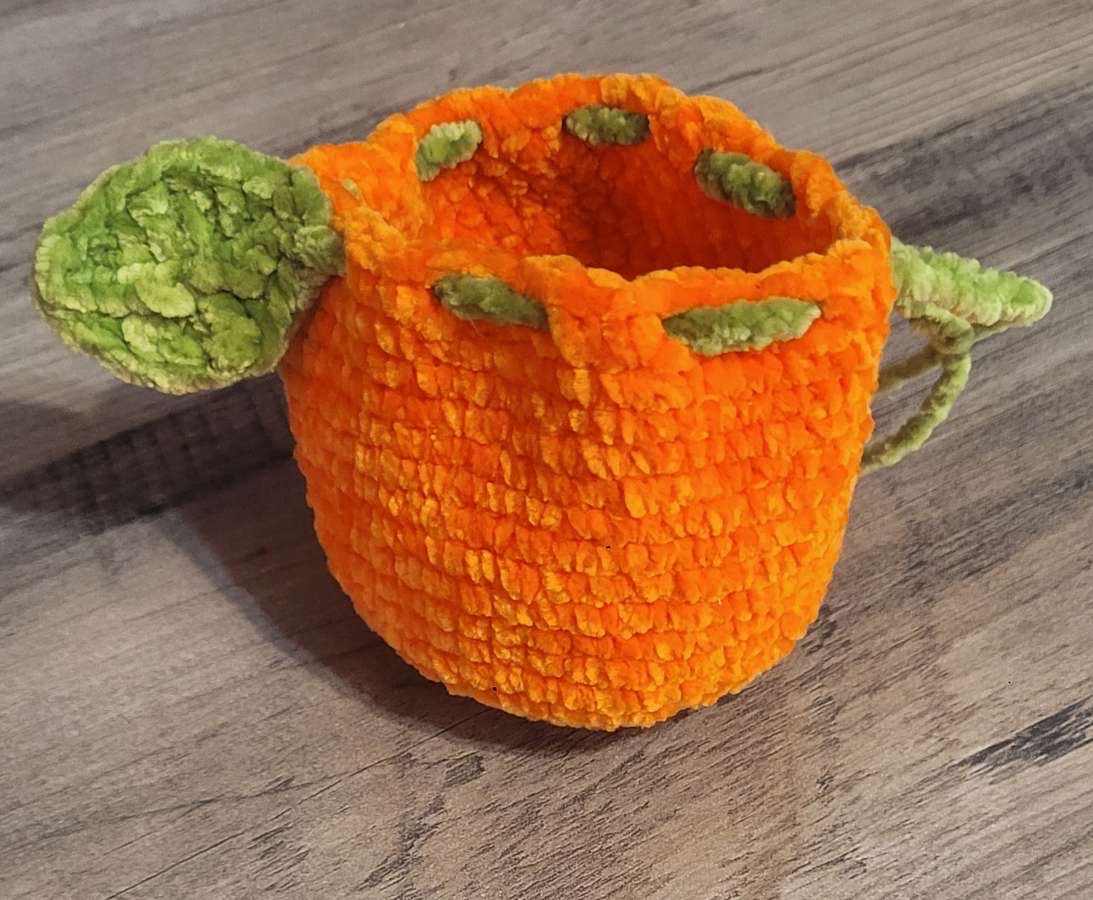 Orange crocheted teapot-shaped pouch with green leaf details